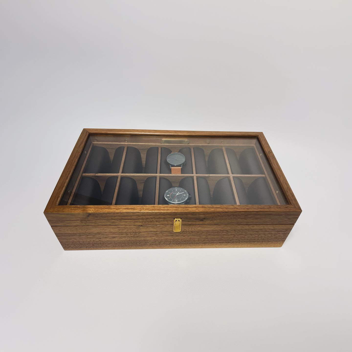 The box photographed from above, two watches resting among the empty cushions