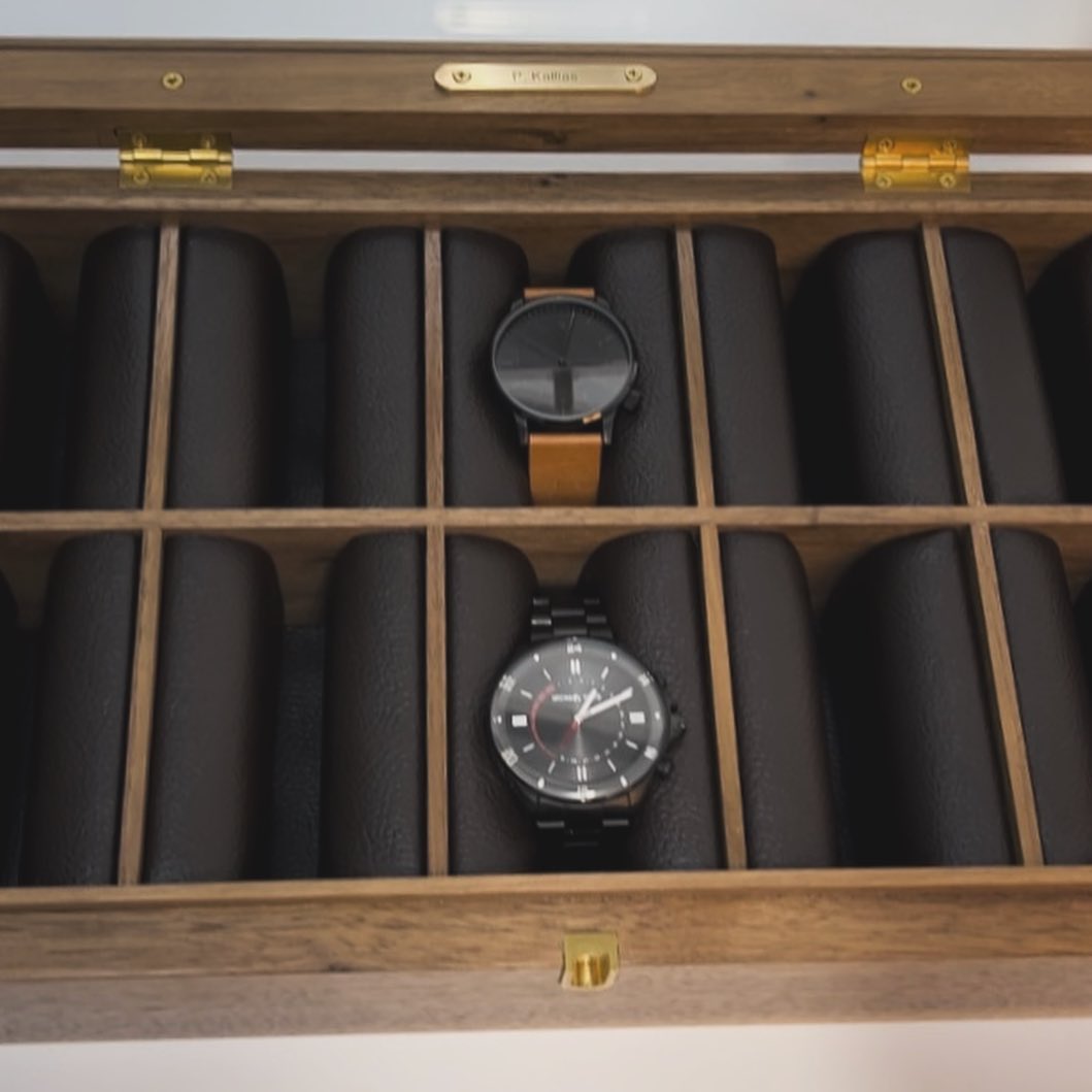Looking down into the open box, an engraved brass nameplate fixed inside the lid above the watches