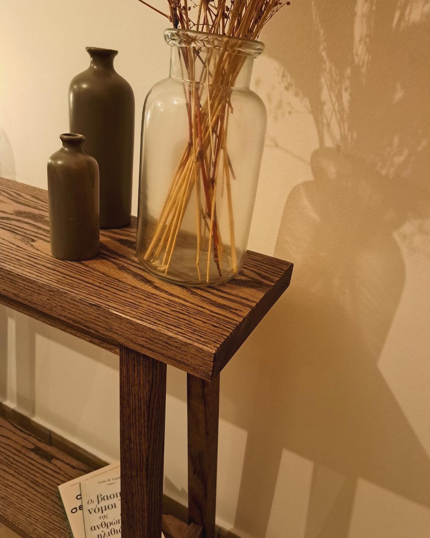Close view of the table top's chamfered edge beside the stoneware bottles and glass jar