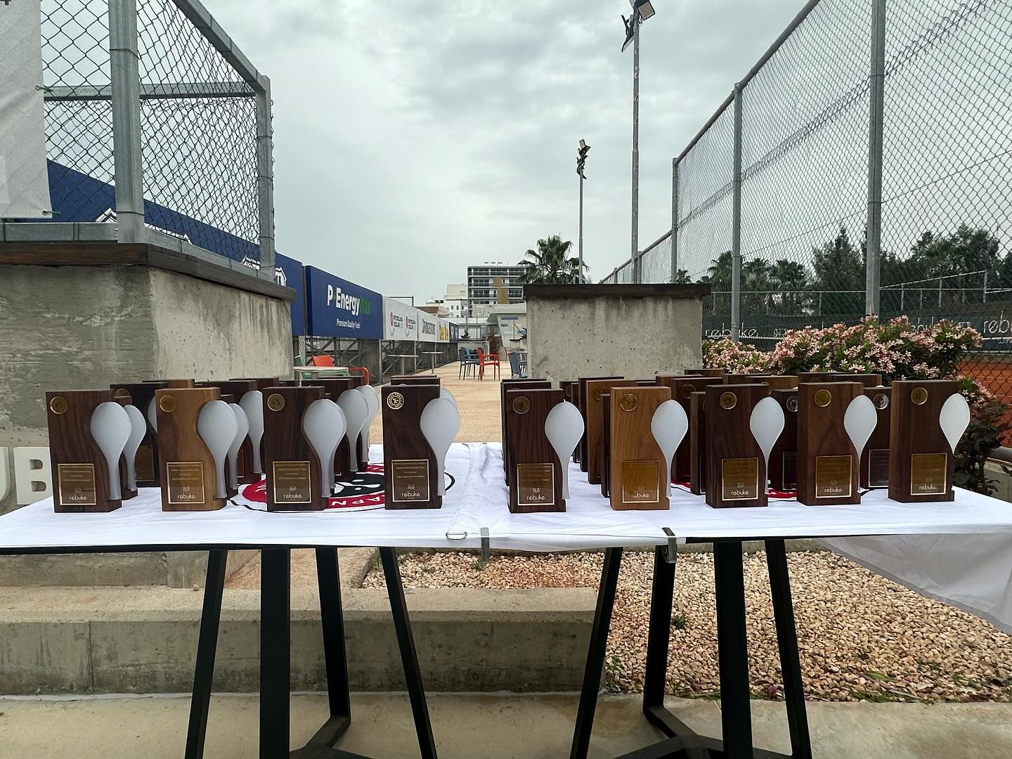 The trophies seen from the end of the table, courts and floodlights receding behind them