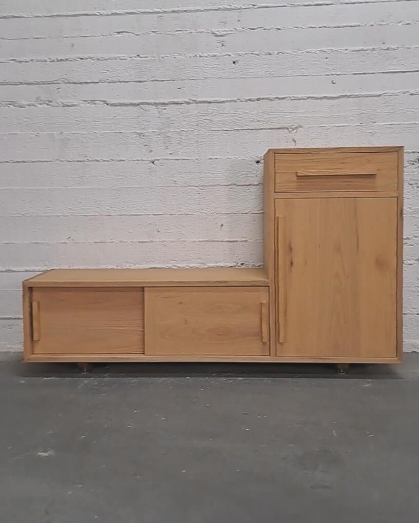 The whole unit head-on against a white brick wall, bench and cabinet forming two levels