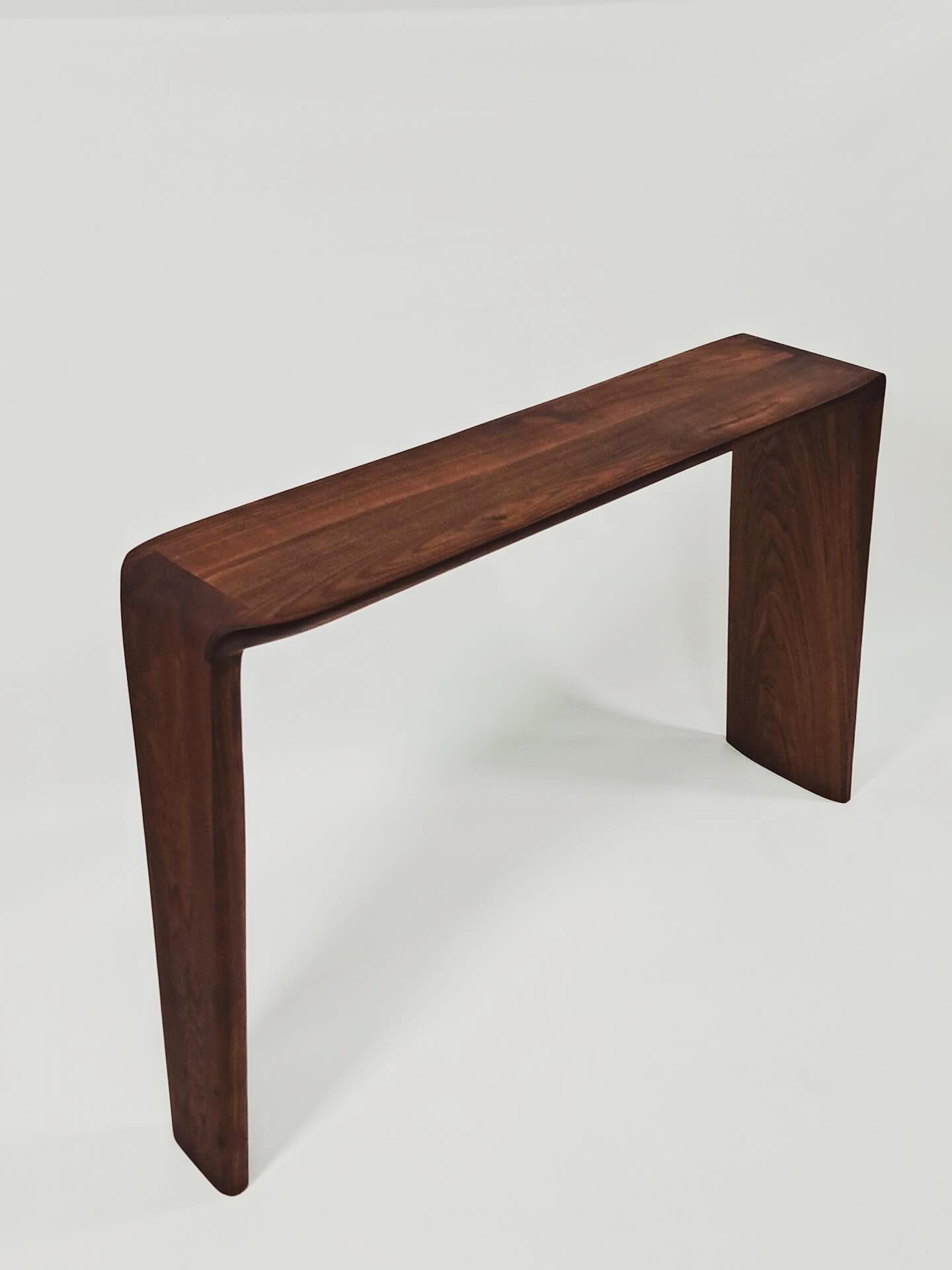 The whole console table at an angle, a slim top carried to the floor on two waterfall sides