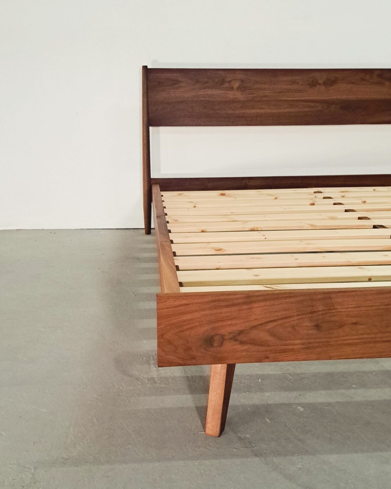 Close view of one corner where the headboard post meets the side rail above an angled leg